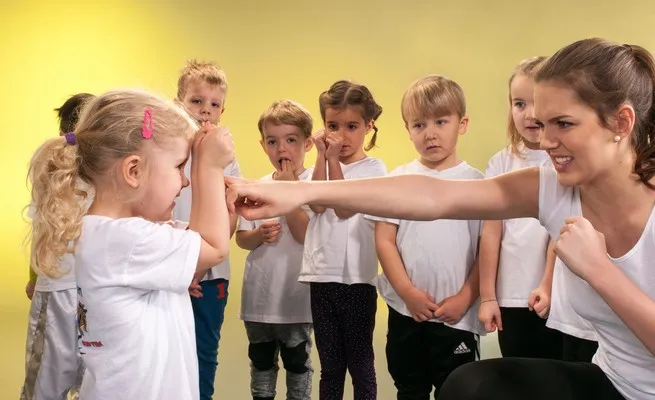 Kinder üben mit der Trainerin Grundelemente aus dem Kampfsport